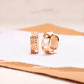 Rose gold circular earrings with three hollowed-out heart shapes.