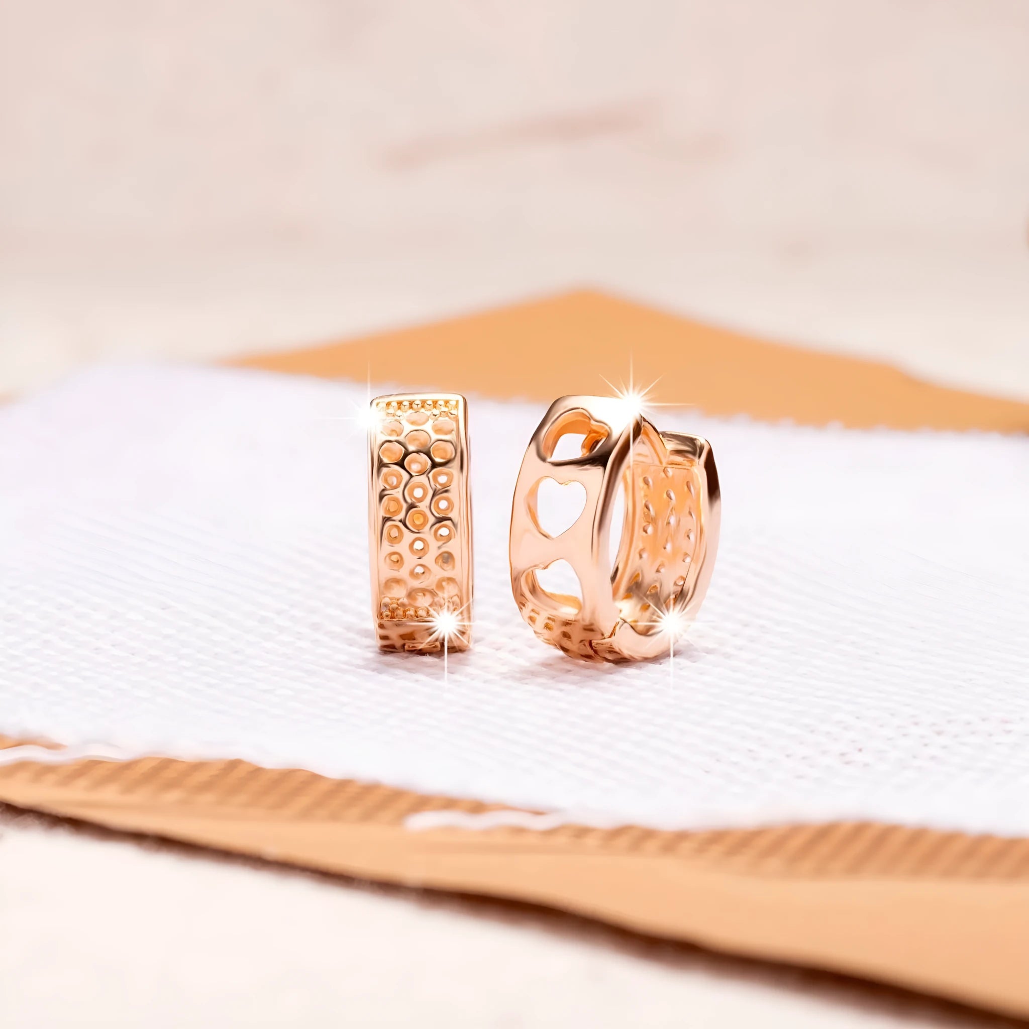 Rose gold circular earrings with three hollowed-out heart shapes.