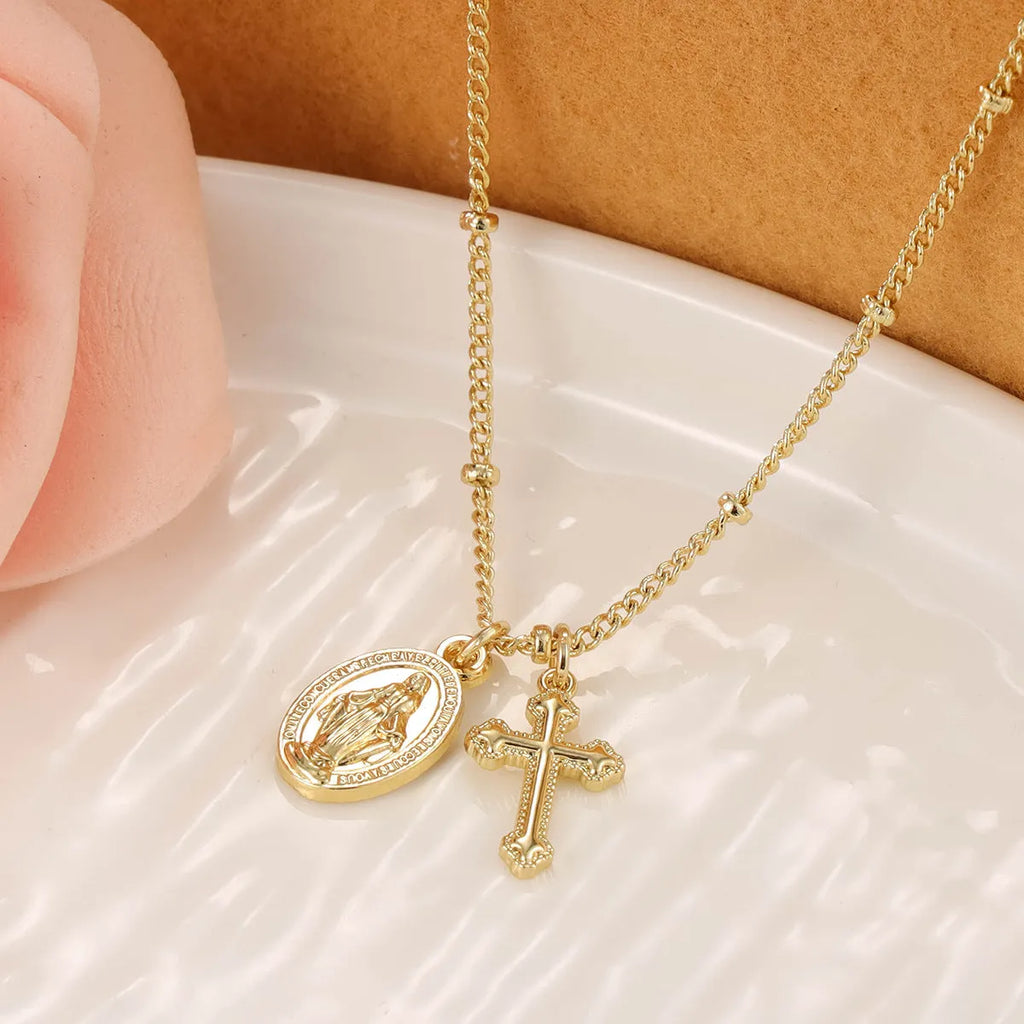 Gold coloured geometric cross necklace with a Virgin Mary ornament on a chain.