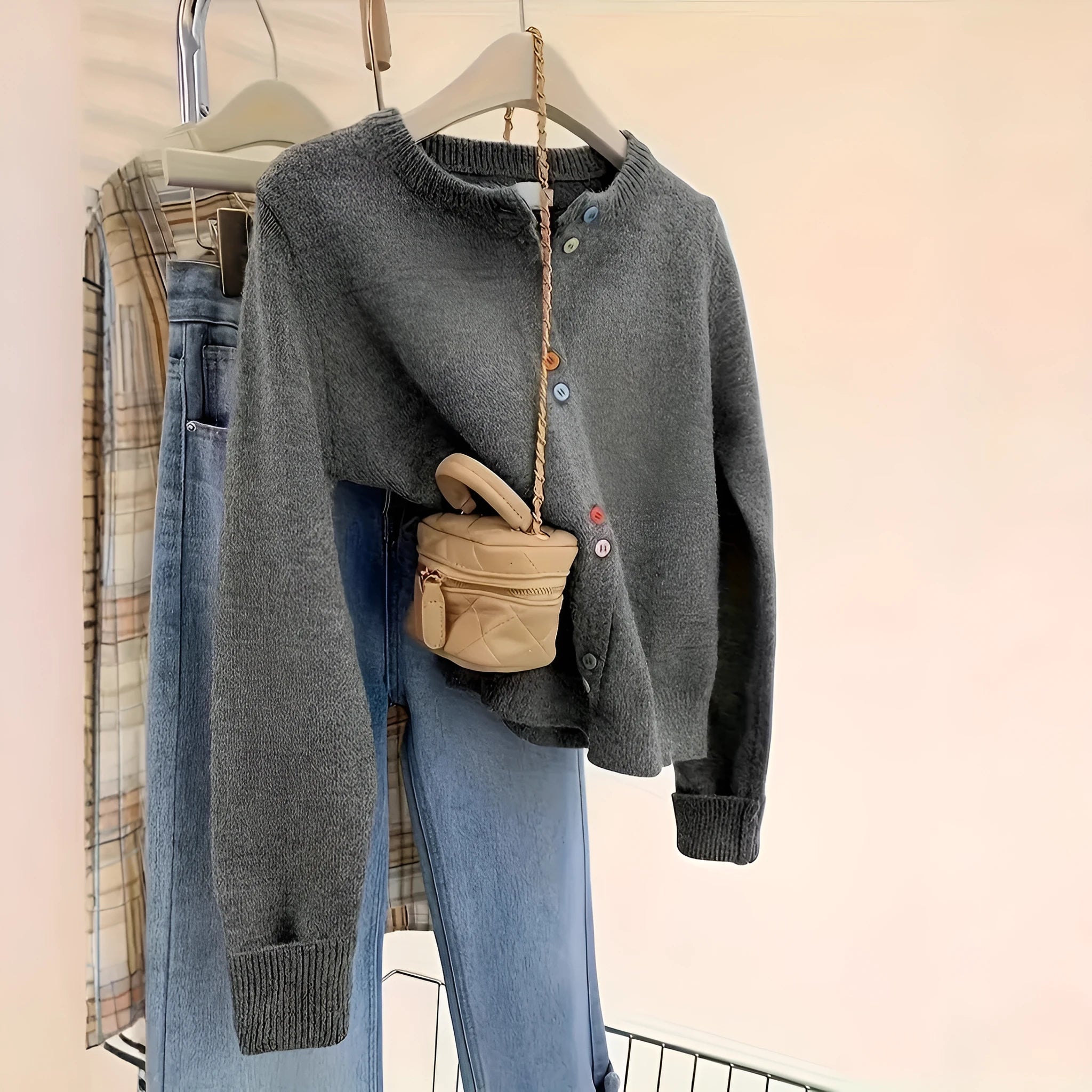 Dark grey women's button-up cardigan sweater with long sleeves on a hanger.