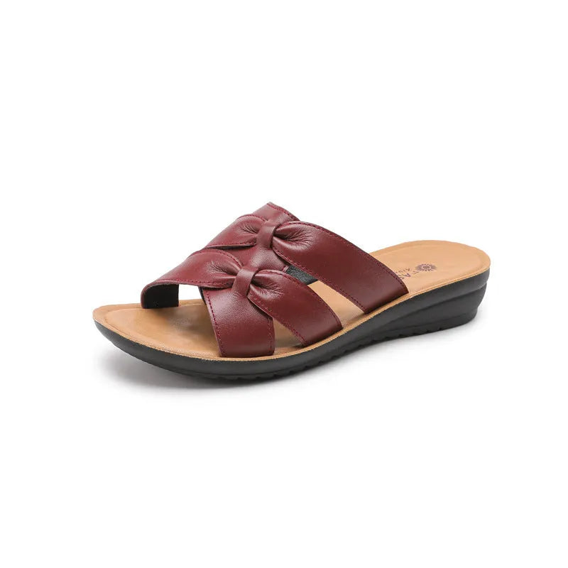 Beige cowhide leather slippers for women with a soft sole, shown from the side.
