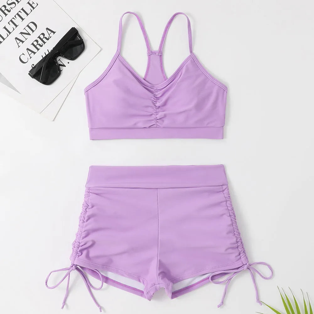 Women's black or purple high-waist split bikini swimsuit with sleeveless top and shorts.