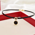 Women's short black clavicle necklace with round gold alloy pendant and leather rope chain on display