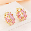Women's geometric U-shaped gold earrings with round black zircon crystals on white background