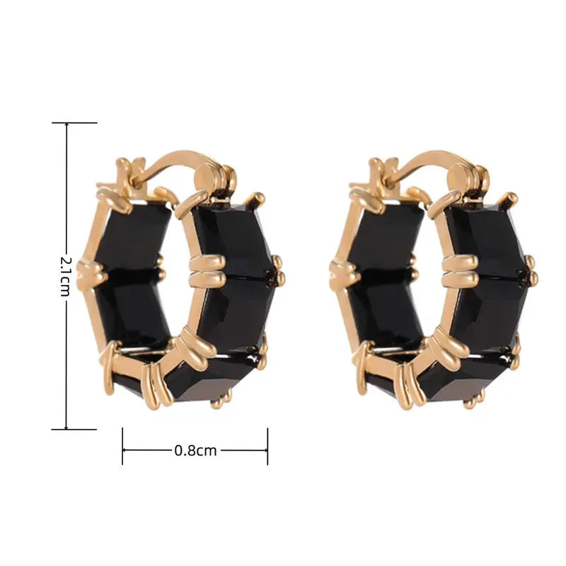Women's geometric U-shaped gold earrings with round black zircon crystals on white background