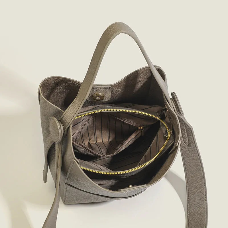 Soft PU bucket messenger bag in elephant gray with visible sewing line detailing, outer sandwich pocket, and single shoulder strap.