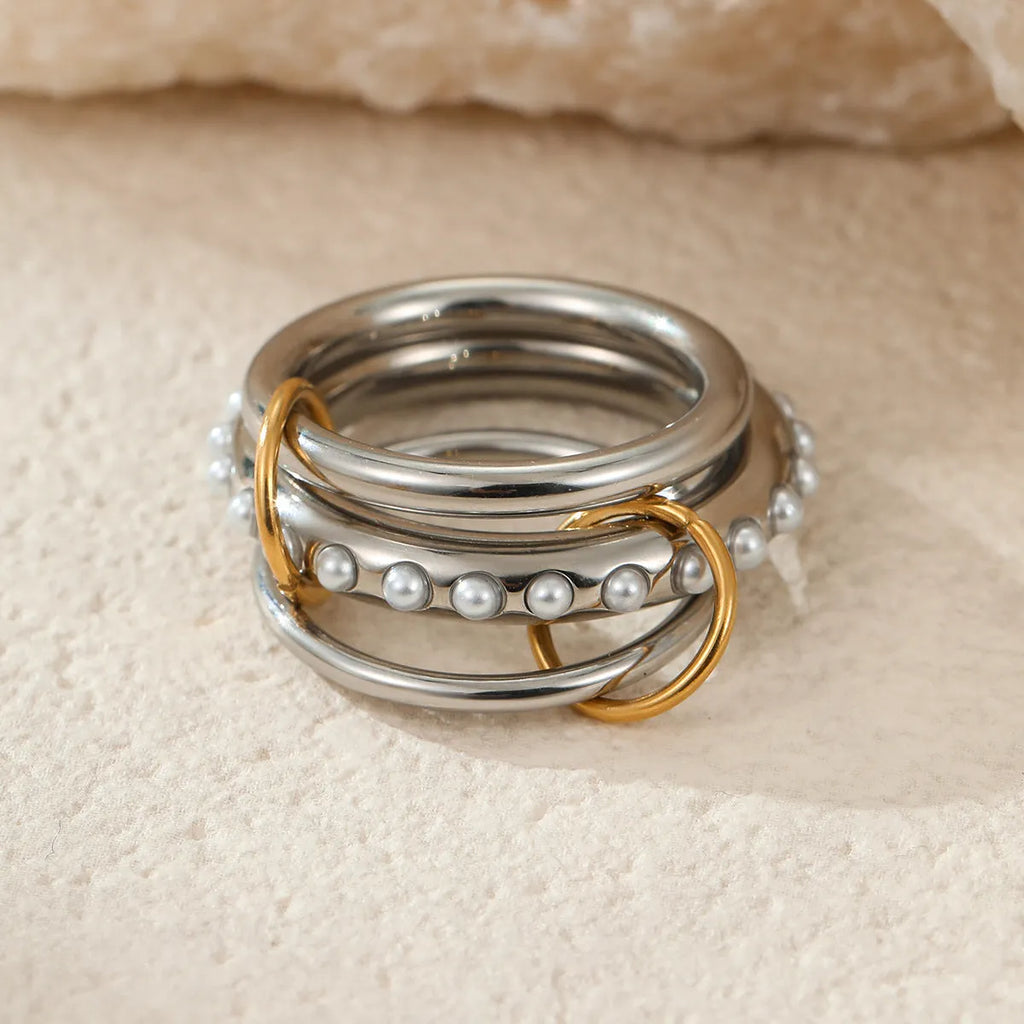 Stacked colour matching stainless steel ring with gold plating and exaggerated design on a woman's hand.