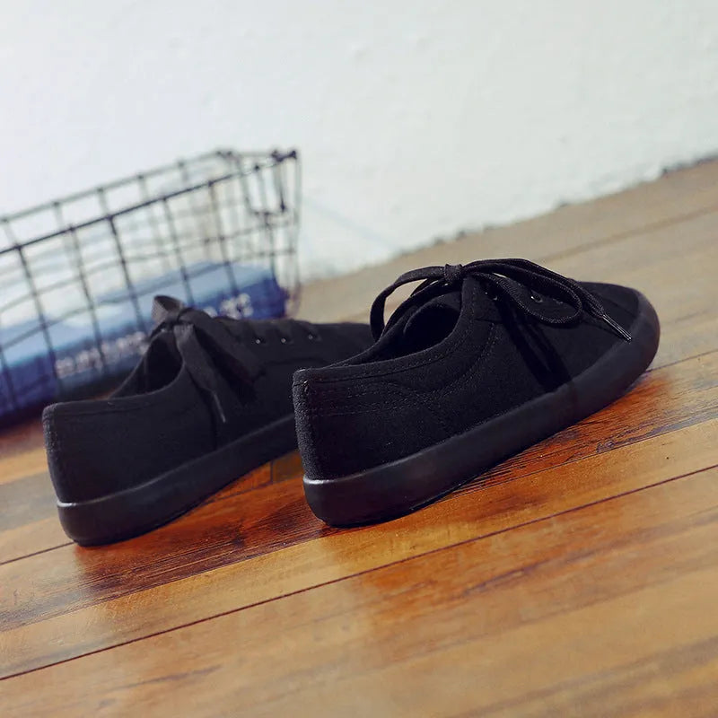 All black women's canvas lace-up work shoes with flat rubber soles.