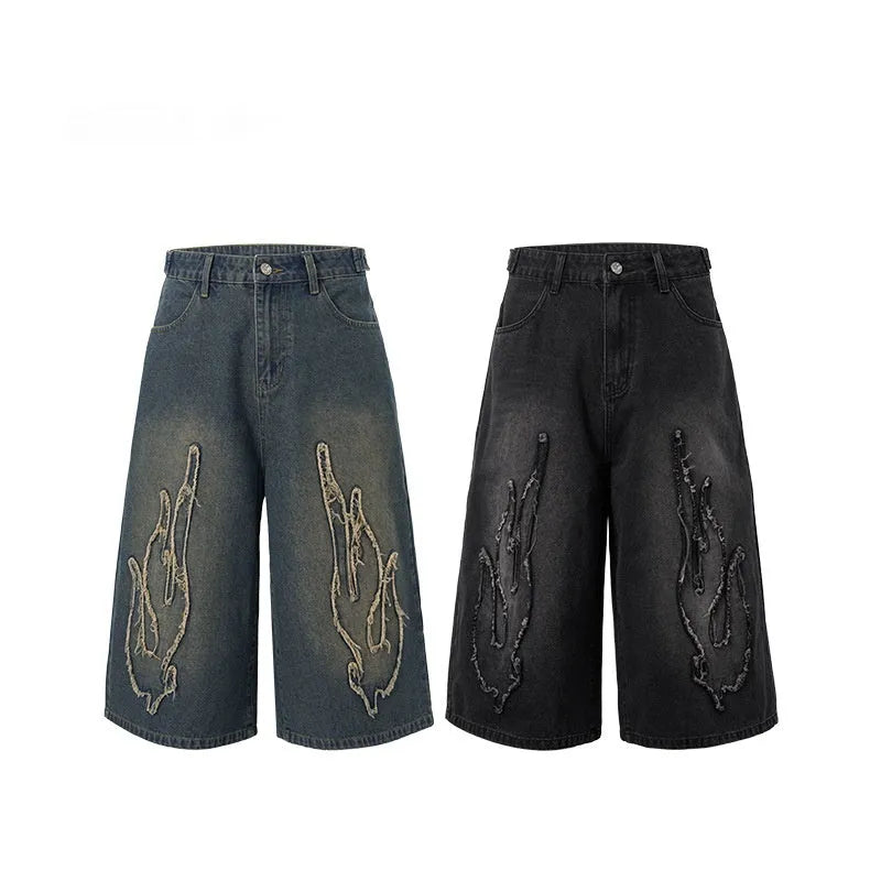 Men's black cropped denim shorts with orange flame embroidery patch on leg