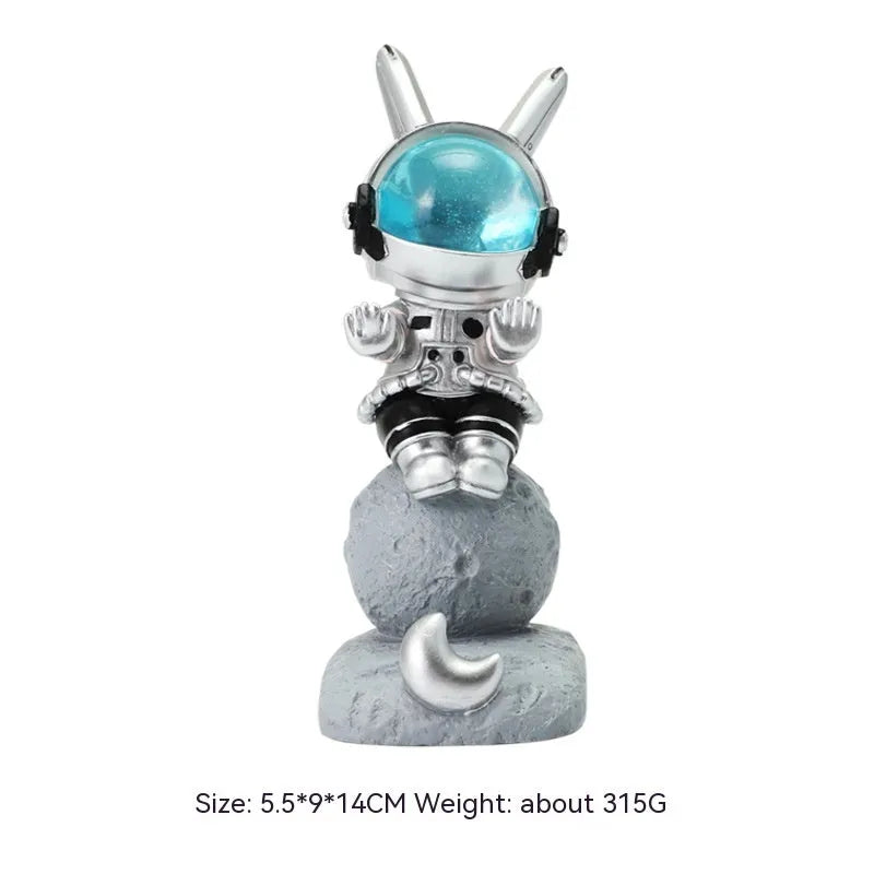 Space Rabbit resin phone stand in pink holding a smartphone on a desktop