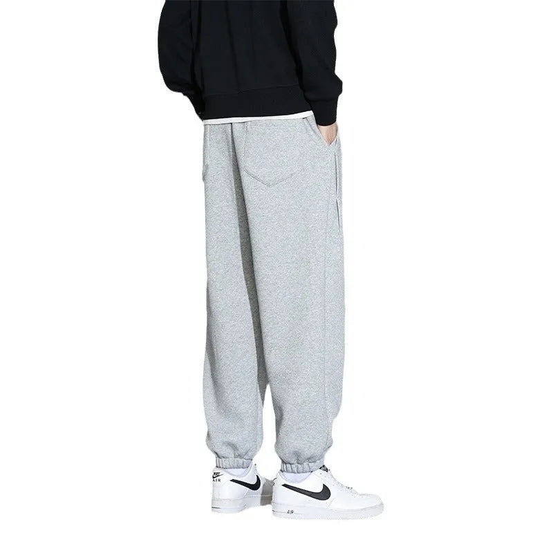 Men's loose grey cotton polyester sports trousers with elastic drawstring waist, laid flat.