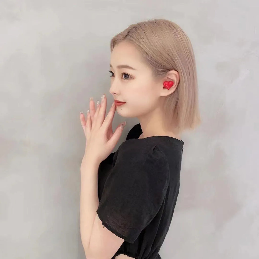 Heart-shaped wireless Bluetooth headphones in red or pink with in-ear design and charging cable