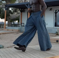 Men's grey pleated wide-leg trousers with an elasticated waistband on a plain background.