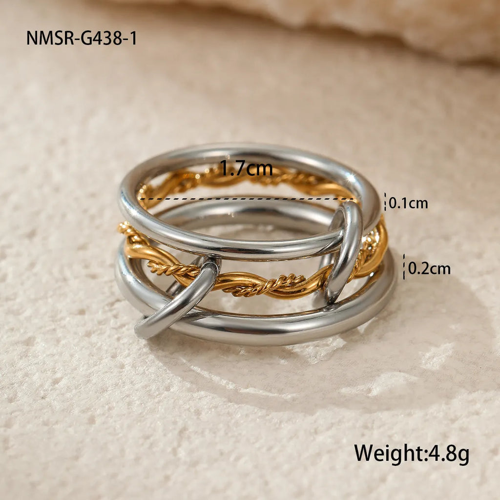 Stacked colour matching stainless steel ring with gold plating and exaggerated design on a woman's hand.