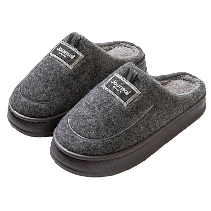 Men's grey suede slippers with a thickened sole on a wooden floor.