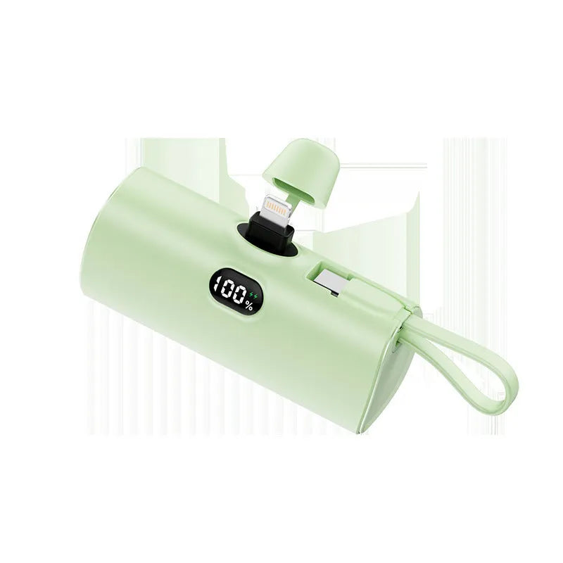Compact black power bank with digital display and a folding AC plug extended, showing its pocket-sized dimensions.