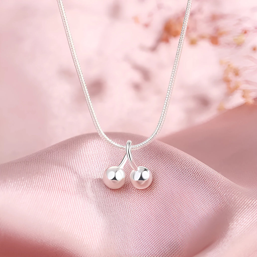 Silver cherry necklace for women with adjustable snake bone chain on a grey background.