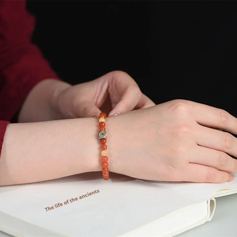 Natural red Nanhong Agate bracelet with a central amber beeswax bead on a white background.