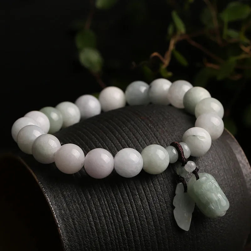 Natural green jade bracelet with a geometric shape and a hanging apple charm on a white background.