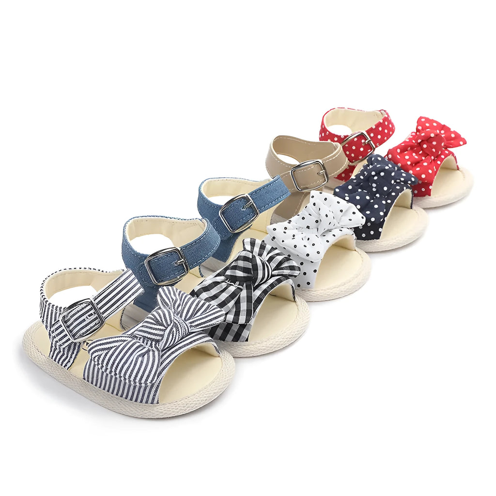 White and black Velcro baby shoes for toddlers, showing low-cut design and strap detail.