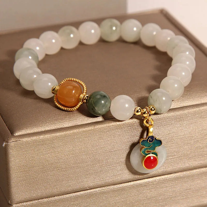 Close-up of a women's ice jade bracelet with carved Xiangyun design, pearl accents, and a jade sliding buckle.