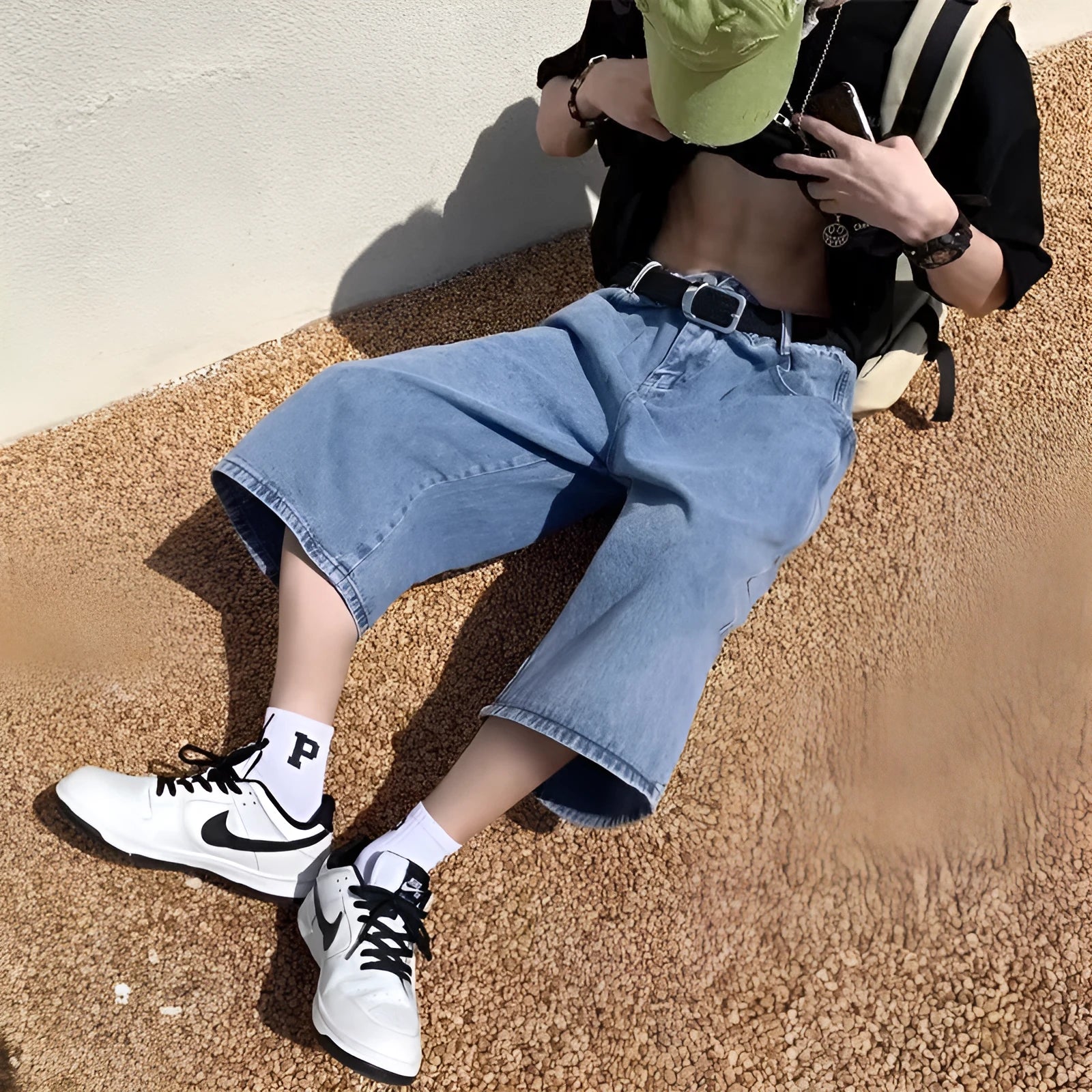 Men's blue washed denim cropped shorts with a high waist and zipper fly on a neutral background