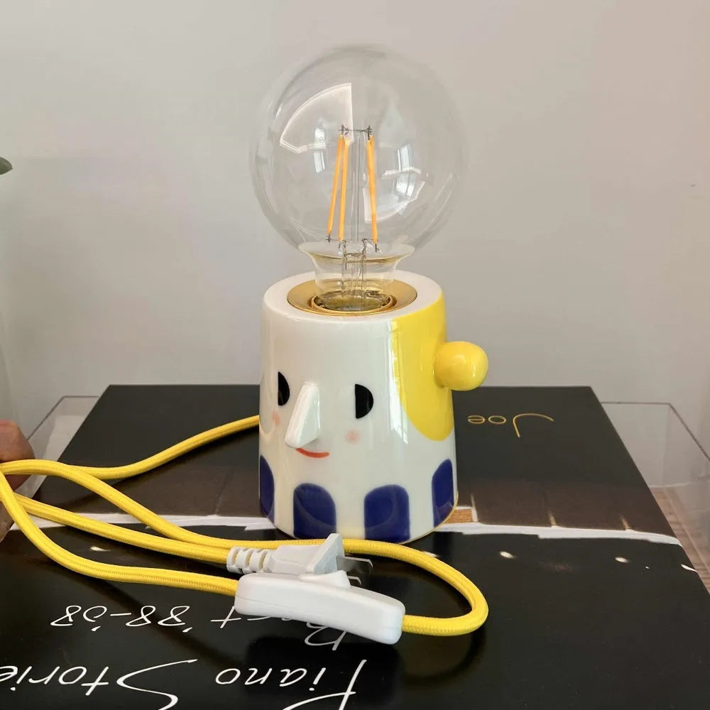 Handmade white ceramic table lamp with a creative ball headlight design on a wooden surface.