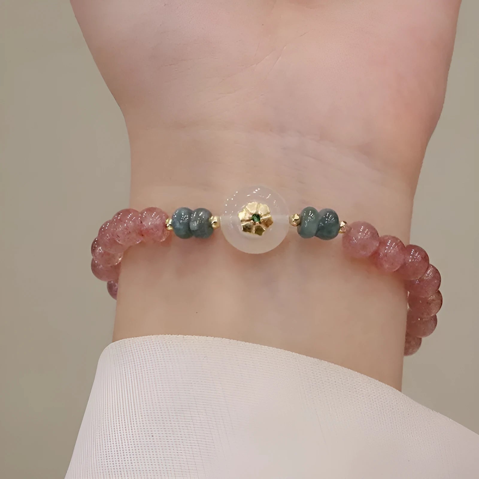 Women's strawberry quartz bracelet with blue water emerald jade pendant, geometric shapes, and traditional Chinese symbolism