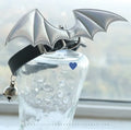 Small black patent leather choker collar with attached devil wings and a bell.