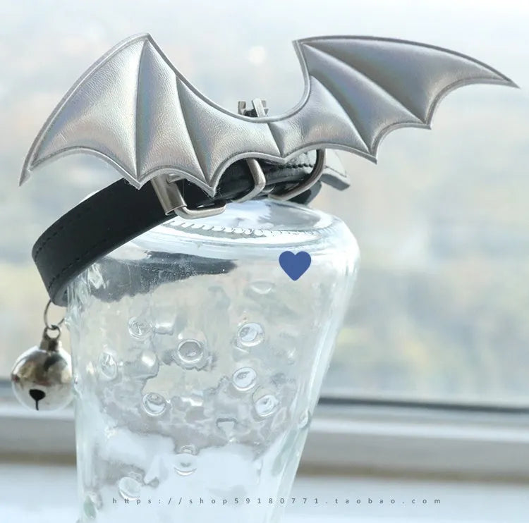 Small black patent leather choker collar with attached devil wings and a bell.