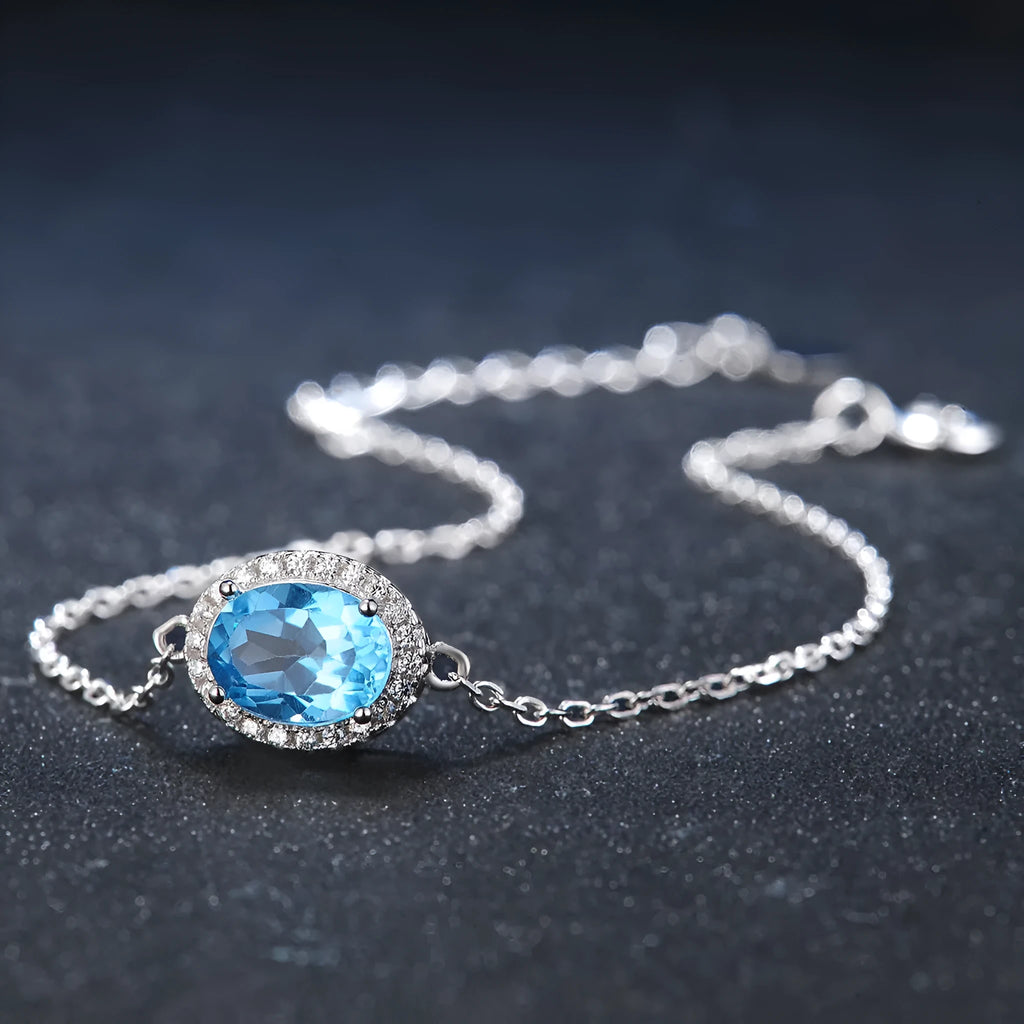 Four-piece sterling silver jewellery set with blue topaz: geometric earrings, ring, pendant, and necklace.