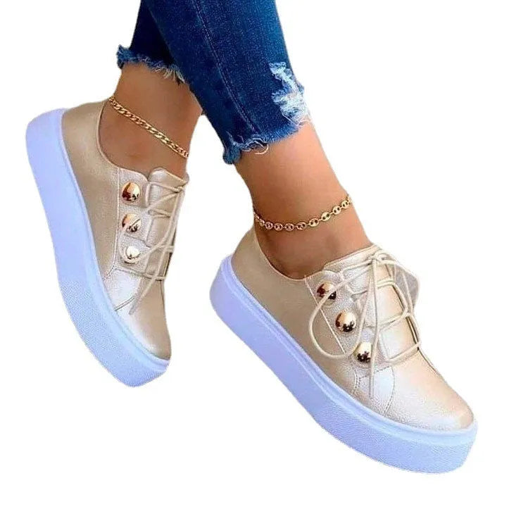 Women's white lace-up flat sneakers with round toe and silver rivet decorative detail.