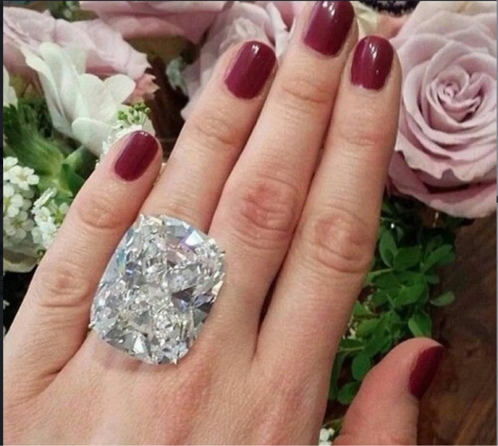 Women's white gold colour ring with a simple inlaid square diamond geometric design on a finger.