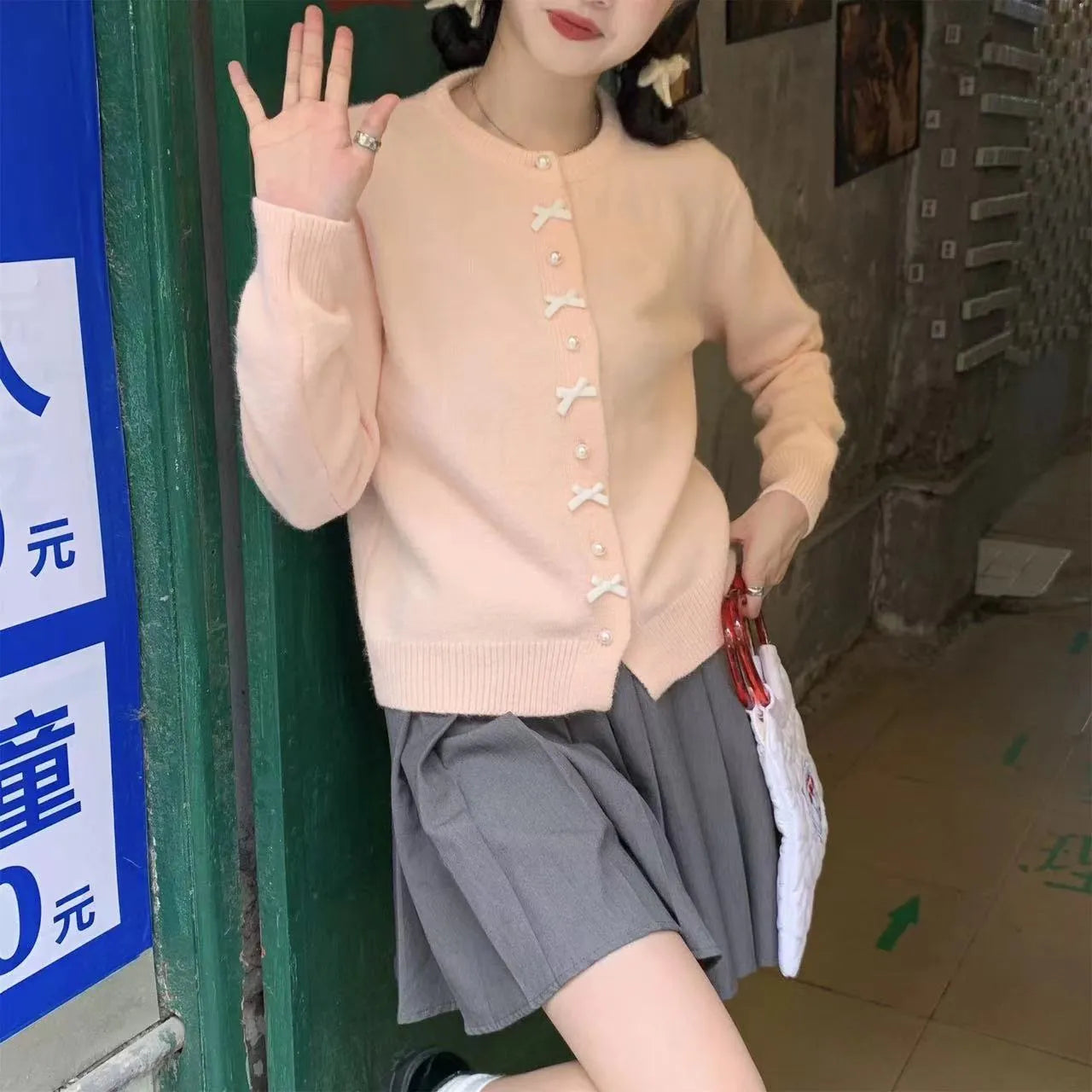Women's solid colour cardigan sweater with bow and pearl buttons, shown in light yellow.