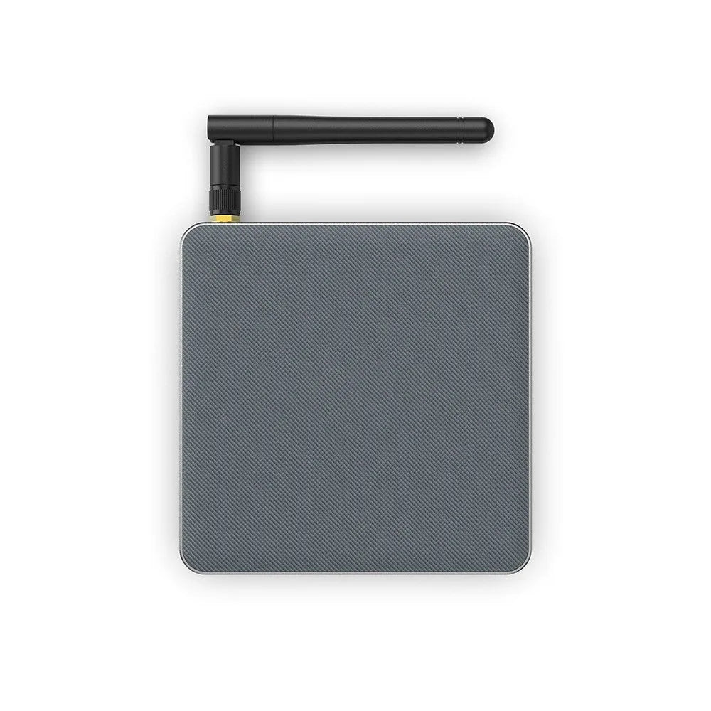 Black Android TV set-top box with HDMI port and remote control on a wooden surface.