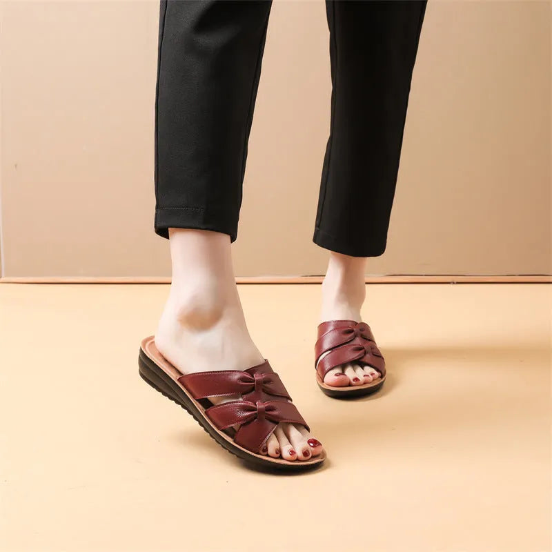 Beige cowhide leather slippers for women with a soft sole, shown from the side.