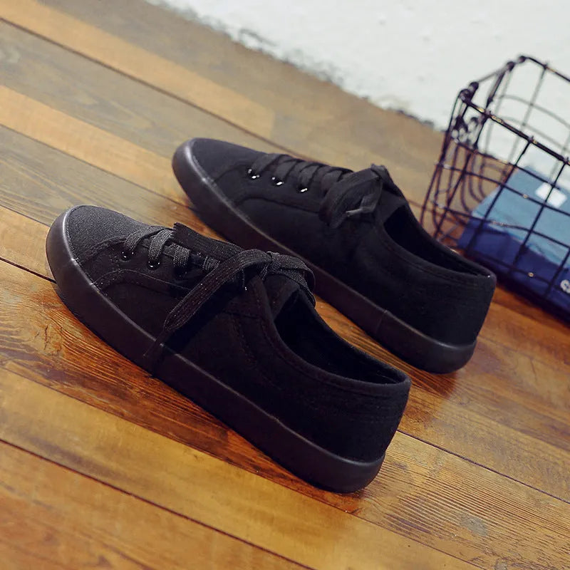 All black women's canvas lace-up work shoes with flat rubber soles.