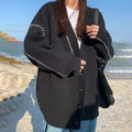 A women's loose-fit knitted cardigan coat in black, showing long sleeves and a solid colour design.