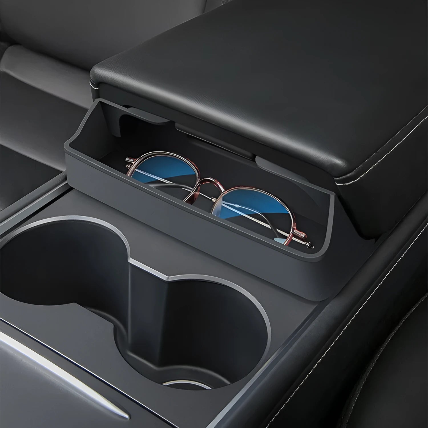 Black silicone sunglasses holder installed in Tesla centre console armrest compartment
