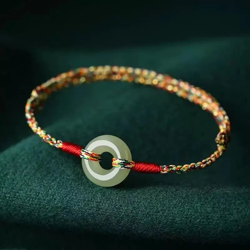 A woven bracelet with a peace buckle on a colourful braided rope.