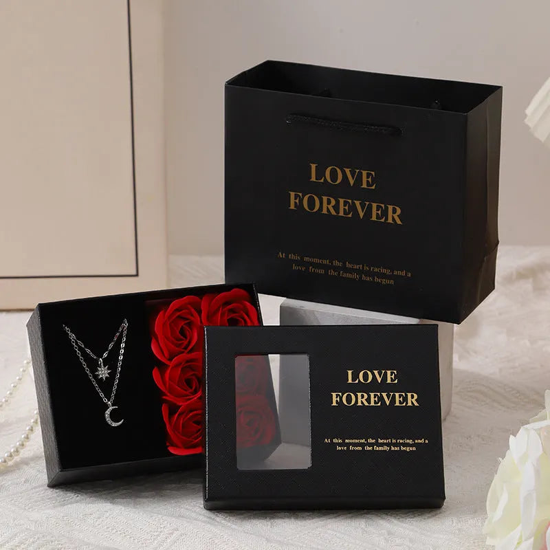 Red Korean-style gift box open to show six pink soap flowers, with a matching handbag beside it.