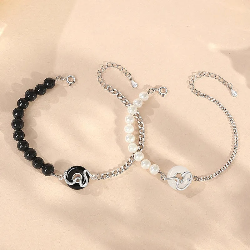 A New Chinese style 925 sterling silver couple's bracelet with a safe buckle, snake motif, and a central obsidian pearl.