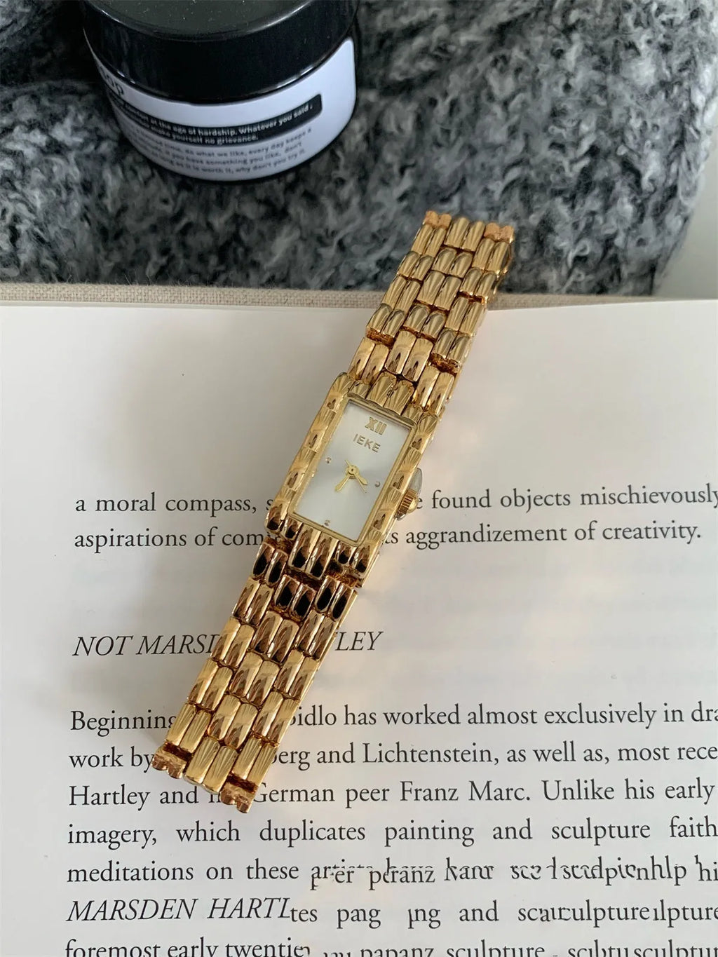 Women's silver and gold bracelet-style watch with a small white dial and butterfly buckle.