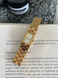 Women's silver and gold bracelet-style watch with a small white dial and butterfly buckle.