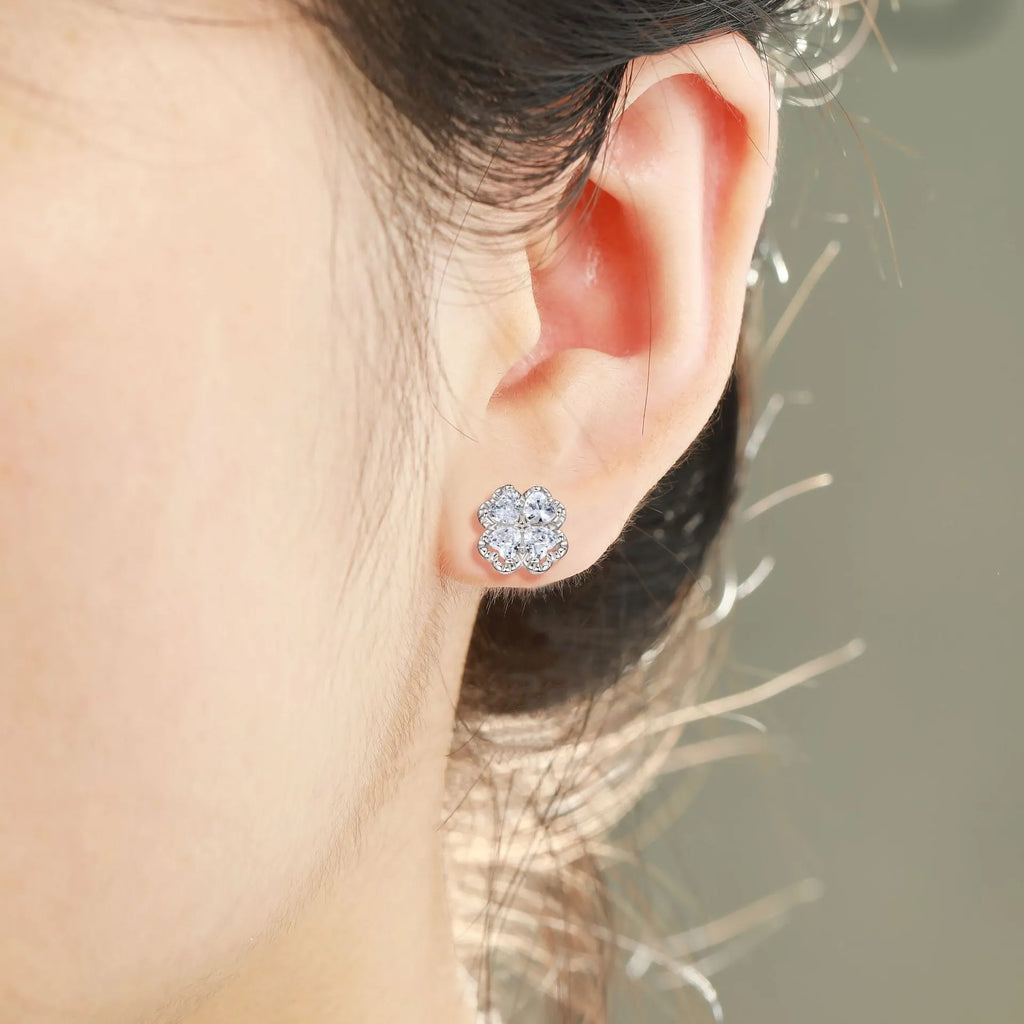 Close-up of women's white gold coloured heart shaped earrings with a four-leaf clover design, made from 925 silver and inlaid zircon stones.