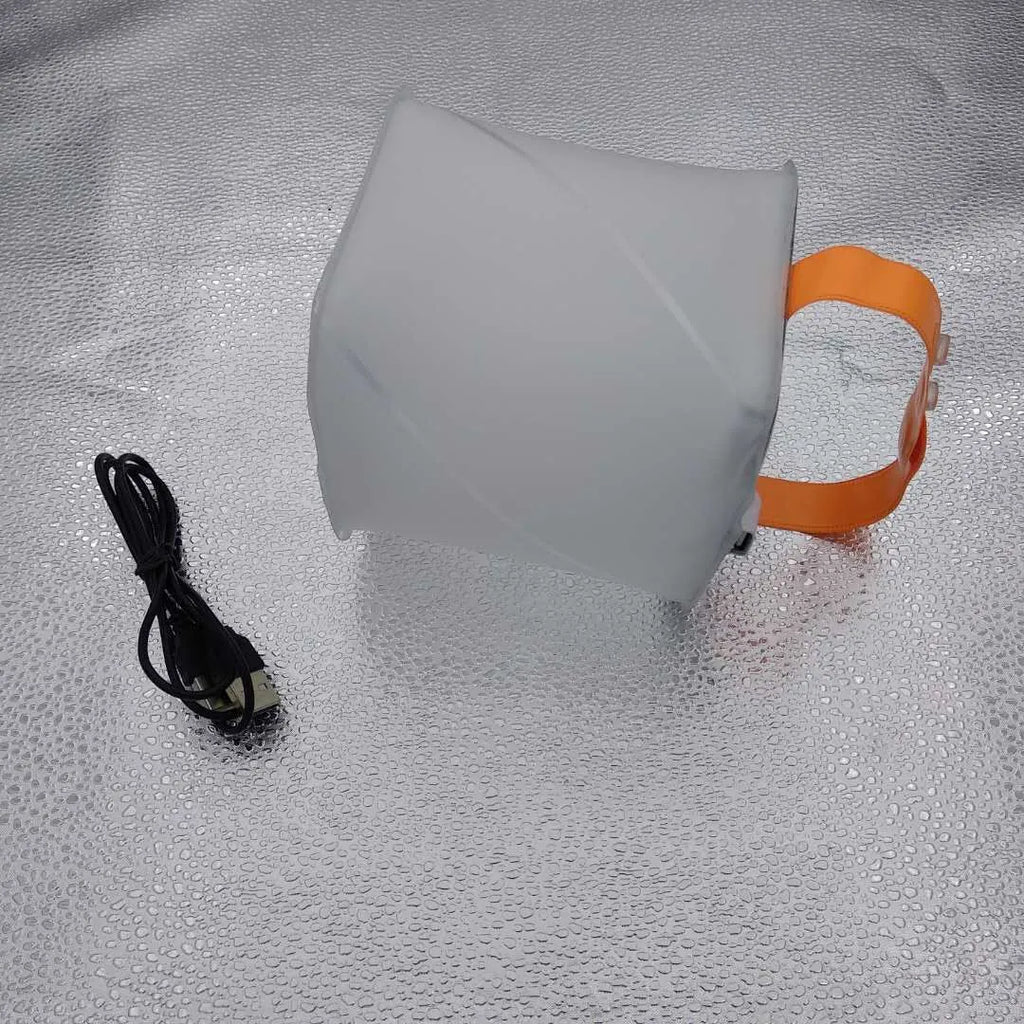 White solar inflatable waterproof camping LED lantern with handle, collapsed flat on a table