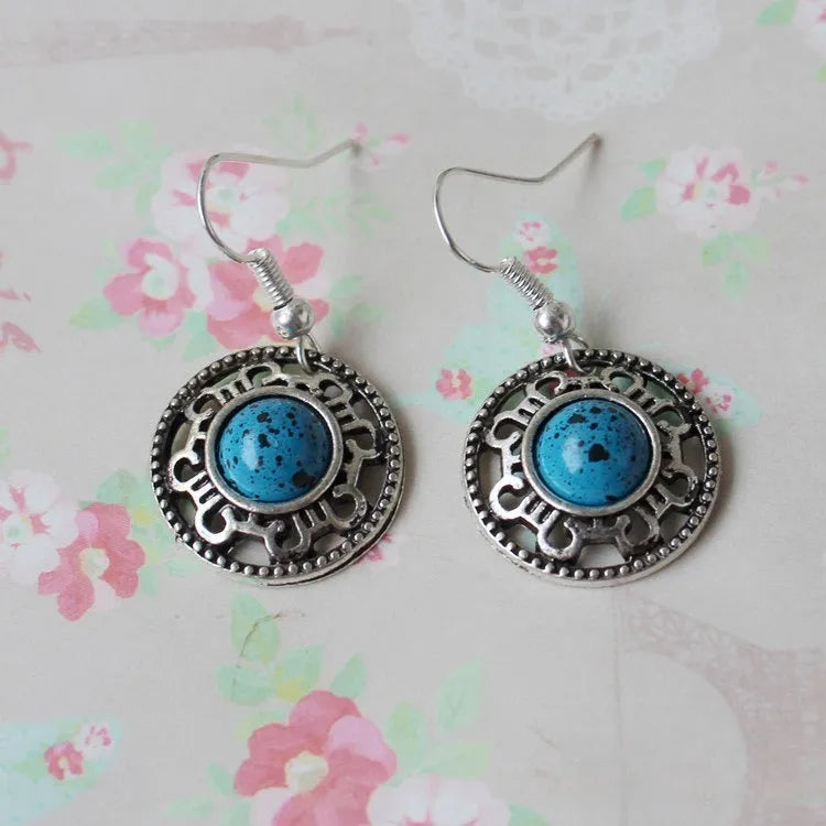 Handmade silver and turquoise ethnic earrings with geometric flower disk and traditional patterns.