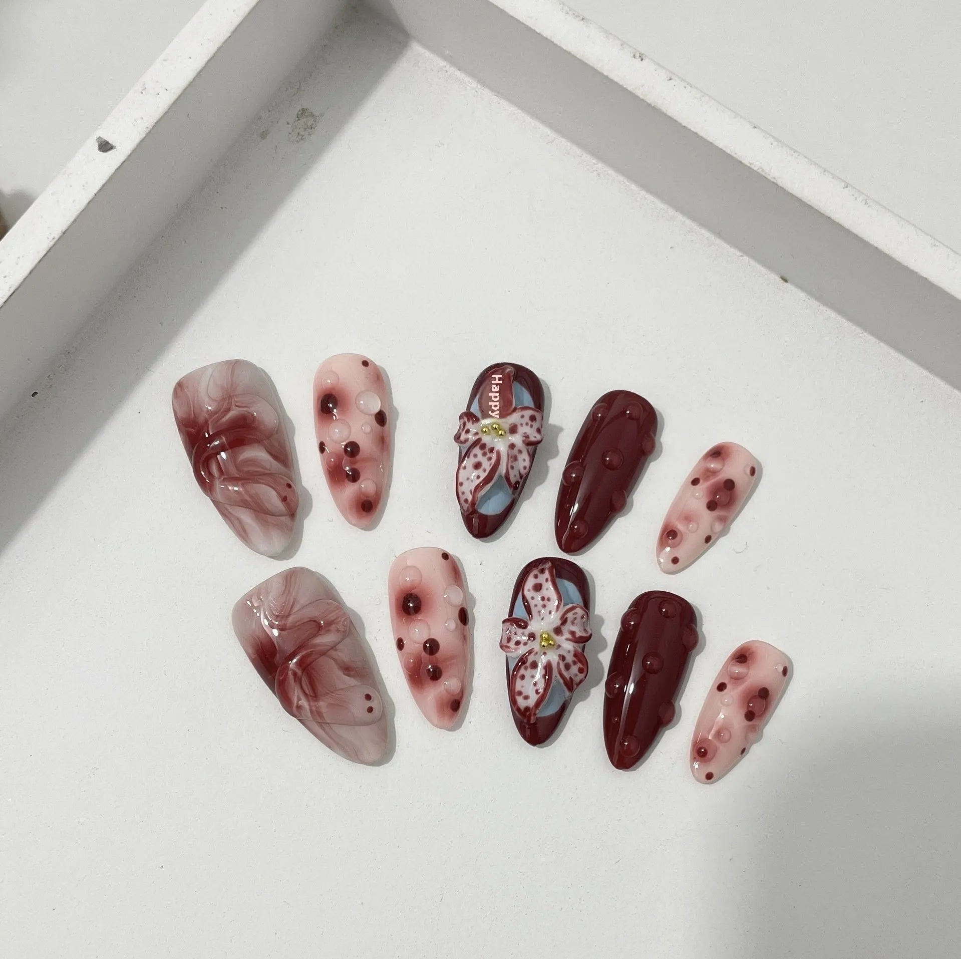 Hand-painted 3D floral artificial press-on nails in almond colour with cat's eye finish.