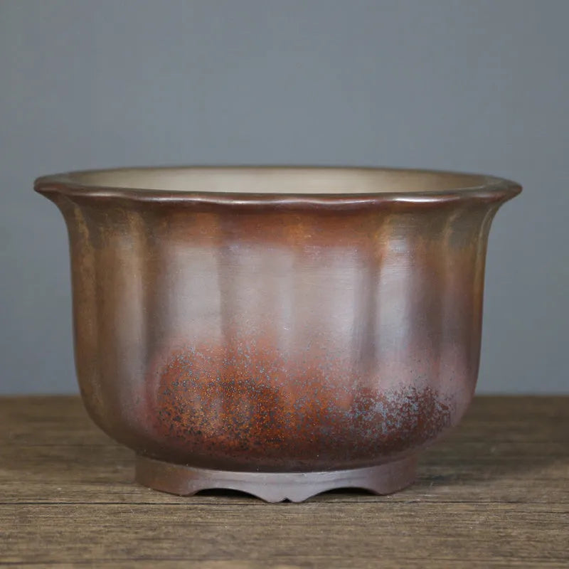 Indoor antique carved purple sand ceramic flowerpot for bonsai plants on a wooden surface.