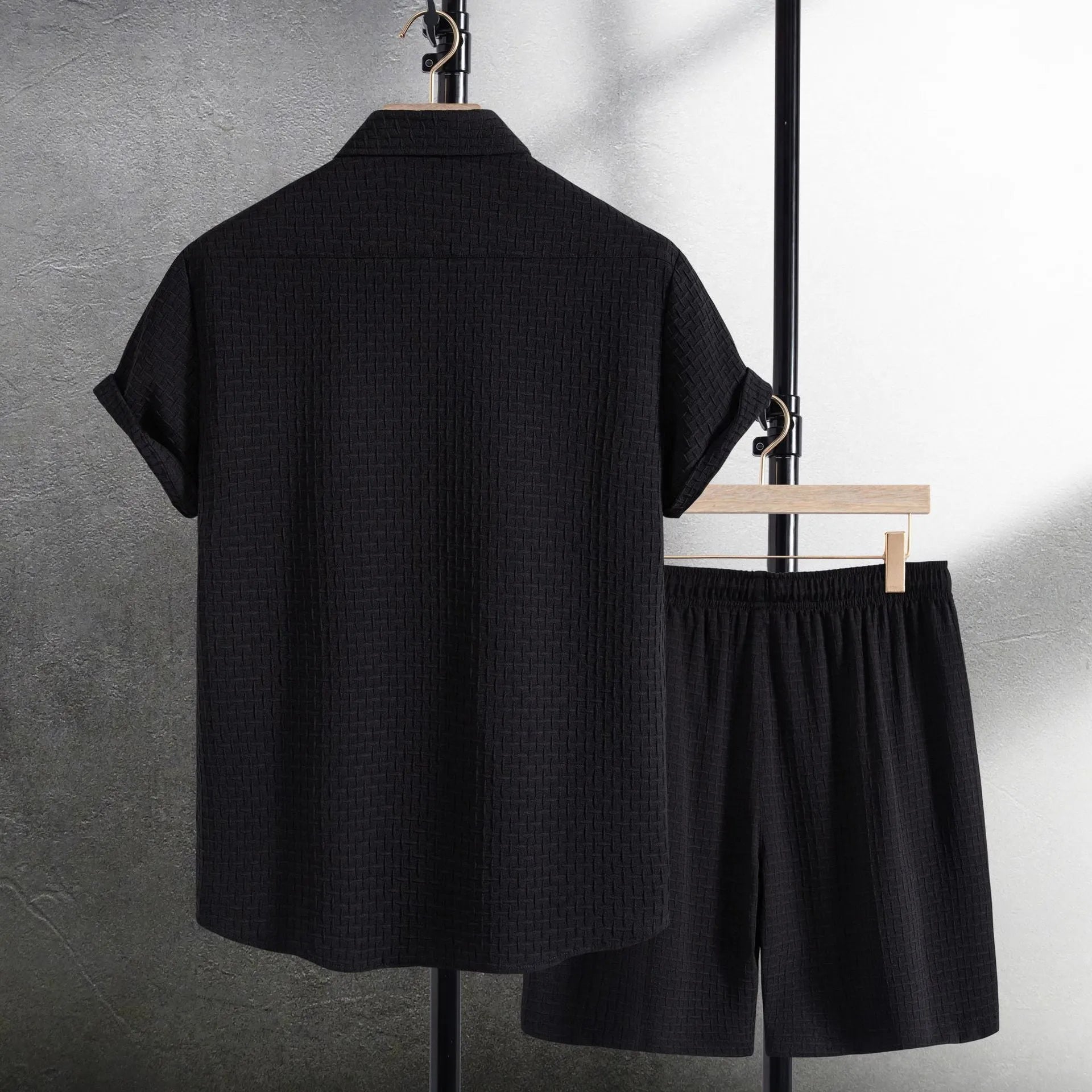 Men's black cotton blend short sleeve shirt and shorts beach suit laid flat.